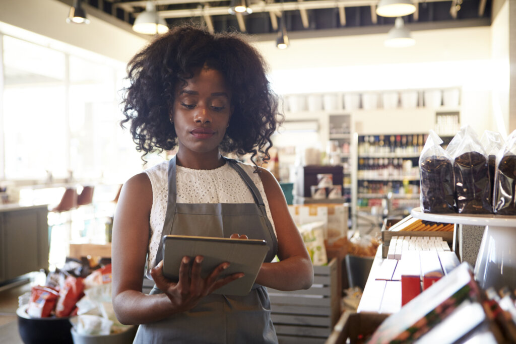 Employee In Deli Checking Stock With Digital Tablet