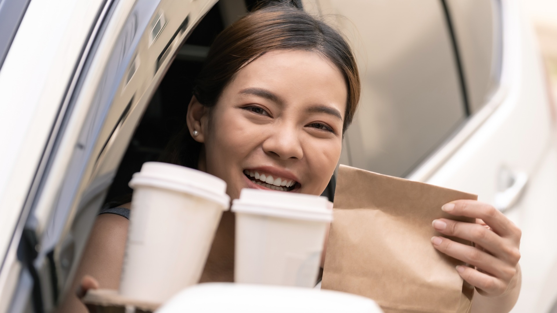woman in car window holding coffee