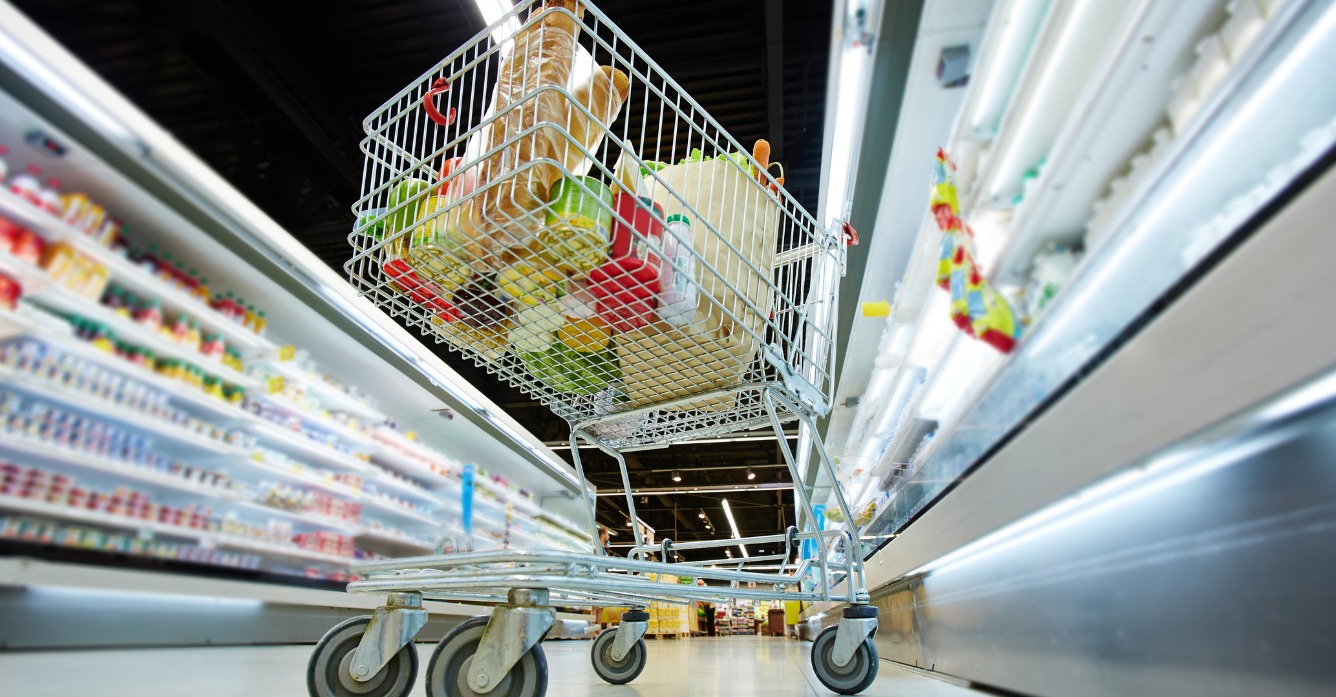 Full grocery cart in refrigerator aisle of supermarket