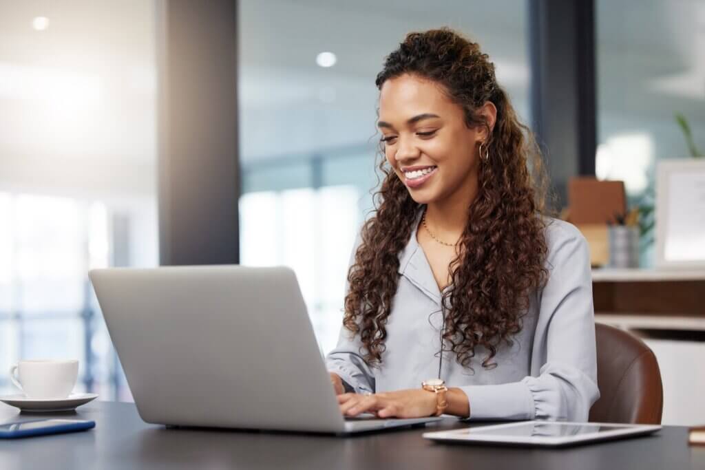female worker sitting at a desk in an office working at a laptop