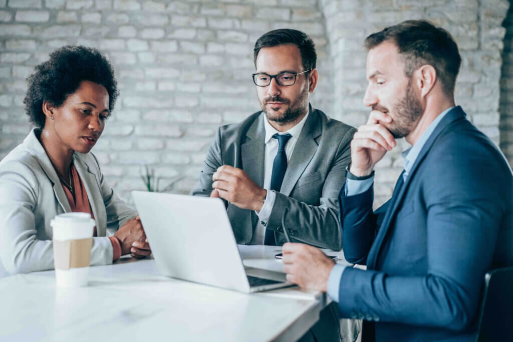 Group of business co workers sitting at a table around a laptop
