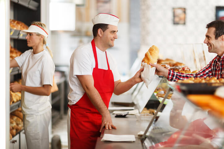 Happy baker and his customer in bakery