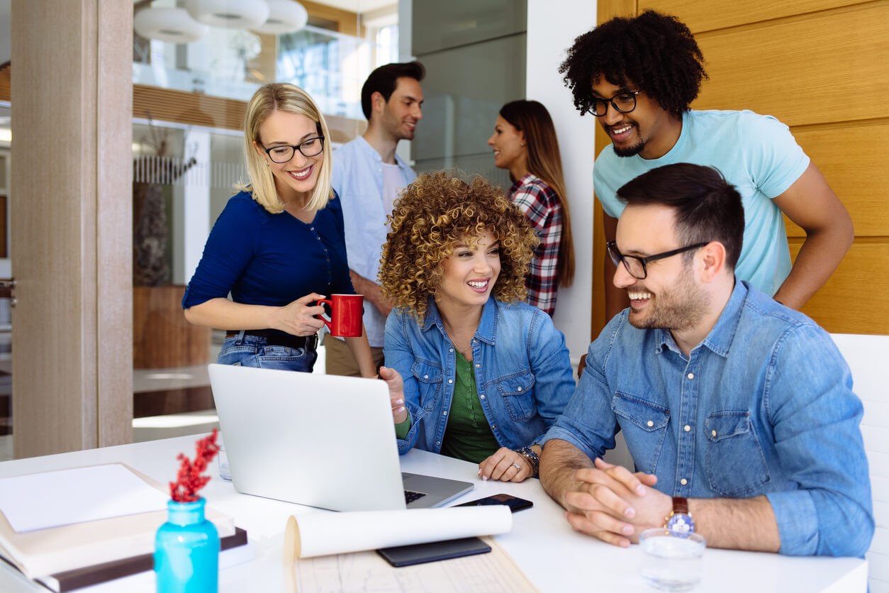 Creative young adult co-workers working together using laptop stock photo